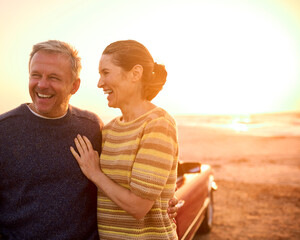 Loving Retired Senior Couple On Vacation Next To Classic Sports Car At Beach Watching Sunrise - 763974015