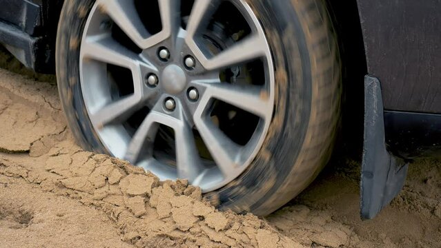 Tires close up. Powerful SUV leaves deep sand. Car glides over rough terrain. Extreme driving conditions in bad weather. SUV vehicle struggling to gain traction in sand, off road in desert