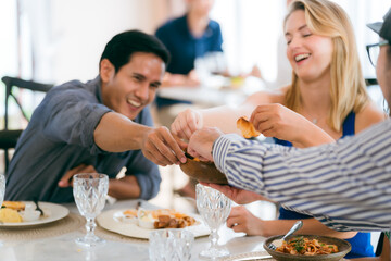 Happy young people laughing enjoying meal having fun sitting together at restaurant table, diverse friends person share lunch at meeting, talking and chatting together in holiday lifestyle - 763975643