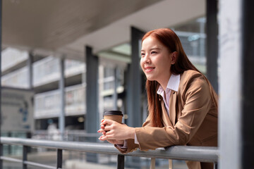 Fototapeta premium Beautiful successful business woman in walking on the street in business town with coffee. Preparation for the working day