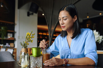 Businesswoman enjoying glass of iced coffee in coffeeshop