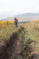 Fototapeta premium Person walking through plantcovered highland field under cloudy sky