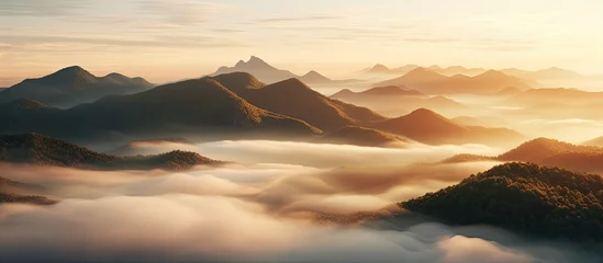 Fotobehang A scenic view of tall mountain peaks that are hidden by thick clouds and fog in the far-off horizon © TheWaterMeloonProjec