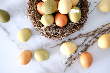 Top view of a nest of twigs inside with yellow, green and light green easter eggs