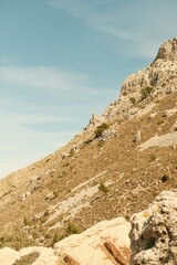 Film style photography of an earth tone landscape in abstract composition. It features a mediterranean mountain, Serra de Bernia, close to alicante, with blue sky.