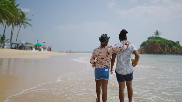 Two men stroll by sea, arms wrapped around each other, exemplifying gay romance. LGBT couple enjoys leisurely walk on sandy beach, symbolizing inclusivity and pride in diverse relationship.