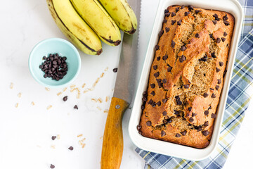 Banana Oatmeal Healthy Bread with Chocolate Chips in a Baking Tin Top Down Vertical Photo on White Background