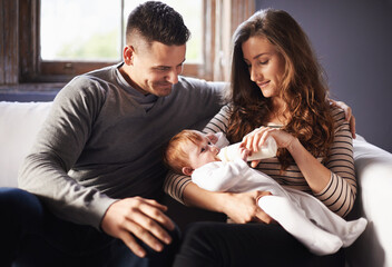 Mother, baby and milk feeding with dad in a family home with love, support and care together. Smile, relax and bottle for youth development and growth with mom and father on a living room sofa