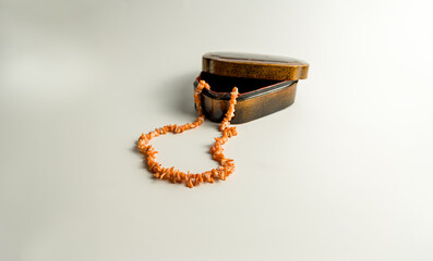 In the foreground, a pink coral necklace emerges from a small wooden box of old-fashioned blurred on a white background. bokeh. copy space.