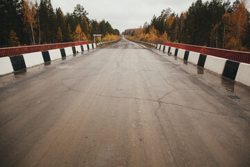 A bridge over road, surrounded by trees and natural landscape - obrazy, fototapety, plakaty