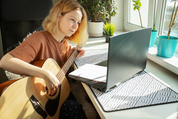 Guitarist learning at home, woman in online guitar lesson, string instrument practice, laptop class
