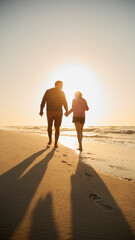 Rear View Of Retired Senior Couple On Vacation Walking On Beach Shoreline Holding Hands At Sunrise - 763998271