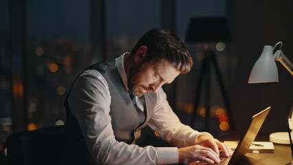 Busy employee working dark office at night. Focused boss typing computer online