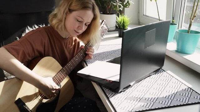 Guitar lesson online, woman playing acoustic, laptop class, musician training at home