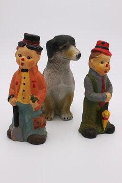 An image of porcelain toys in the form of two men and a dog on a light background.