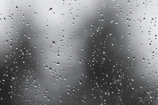 Dirty wet window glass with droplets and gray blurred environment