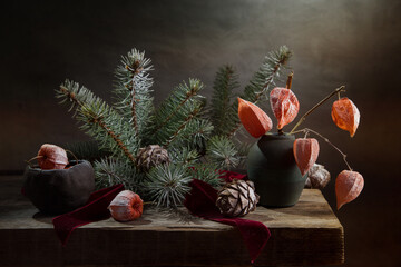 Winter still life with a bouquet of snow-covered spruce branches, physalis and pine cones