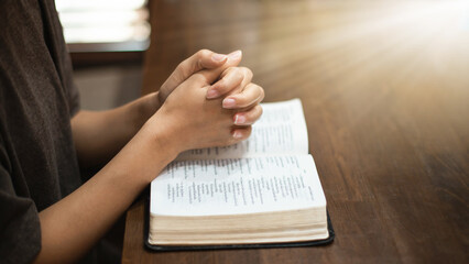 Obraz premium Christian woman's hands resting on a Bible pleading with God.