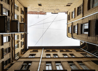 A symmetrical view of a building's courtyard with architectural details, looking up towards. Dark...