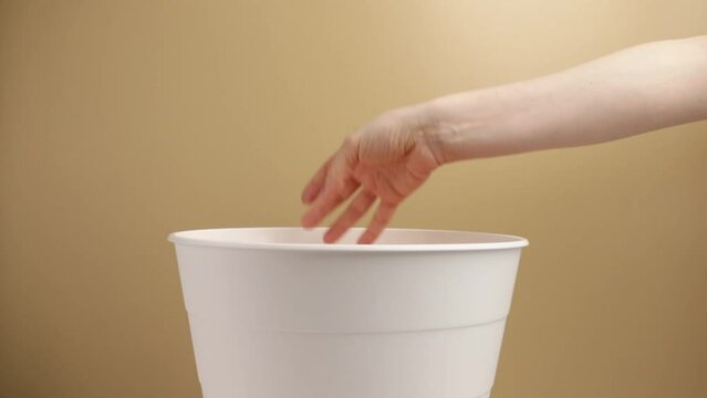 hand throws shampoo dispenser into trash can