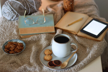 Cup of tea or coffee, cookies, books, glasses, e-reader, almonds, ball of yarn, knitting needles...