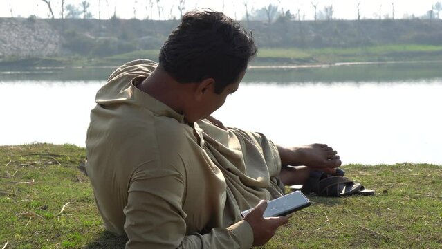 person sleeping near lake and using mobile. Man sleeping near a lake. relaxing. enjoying. holidays concept. 240fps Slow Motion