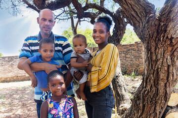 african family with three kids standing in the backyard, in the township, late afternoon,
