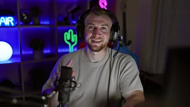 Smiling bearded man in headphones using microphone in neon-lit gaming room at night