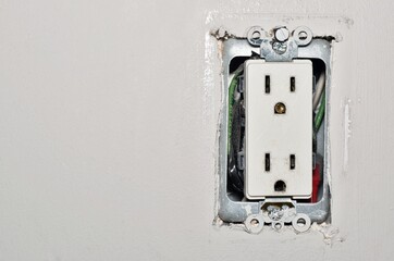 Dangerous power outlet with a broken plug prong inside, and exposed wires without the plastic wall plate safety cover. Old electrical socket with safety concept with copy space.