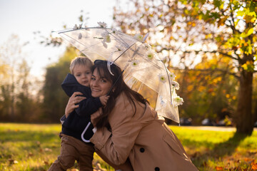 A mother and son stroll through a spring park. The woman holds a flower-adorned umbrella. It's a...
