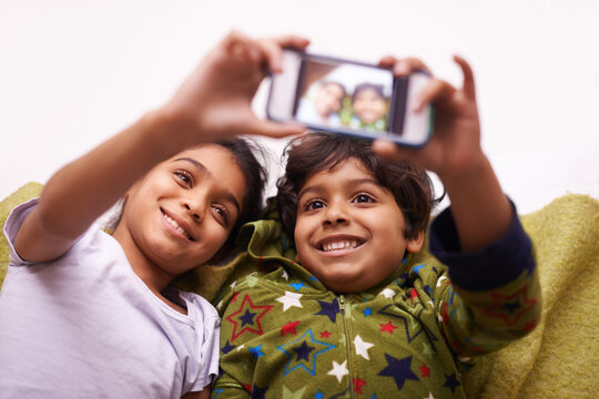 Phone screen, selfie and kid siblings on a floor for fun, vacation or memory at home from above. Smartphone, photography and children in a living room smile for social media, blog or profile picture
