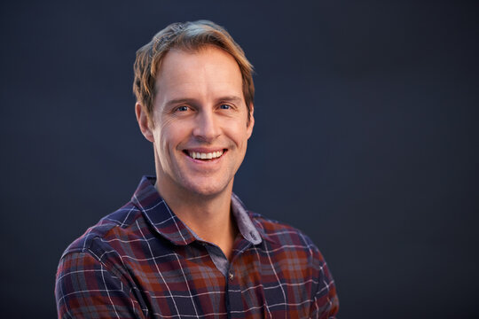 Happy, nerd and portrait of man in studio, dark background and smile with pride or confidence in fashion. Geek, face and person with plaid pattern on shirt or relax in casual style on mockup space