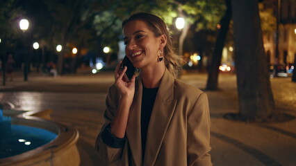 Attractive woman speaking mobile phone on city square. Smiling girl enjoying