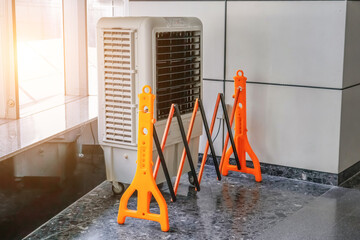Portable air conditioner or mobile air cooler in modern public place space, fenced with a folding...