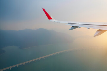 View of an airplane wing and a bridge in the strait during takeoff