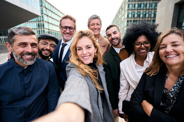 Selfie of a cheerful team of diverse business people in formal suit looking smiling at camera...