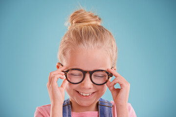 Child, glasses and optometry vision in studio or healthy eyes on blue background for prescription, lenses or mockup space. Female person, smile and frame spectacles or development, growth or wellness