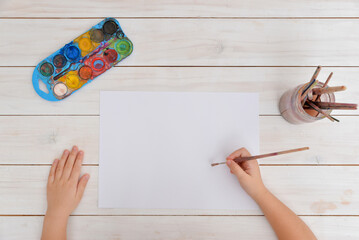Hands use brush for watercolor painting on clean paper. Concept of creativity, art, childhood,...