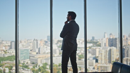 Thoughtful man looking panoramic window in office. Legal manager contemplating