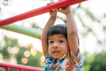 Adorable preschool boy enjoying bar lifting in outdoor playground in city park
