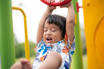 Adorable preschool boy enjoying bar lifting in outdoor playground in city park - 764036691