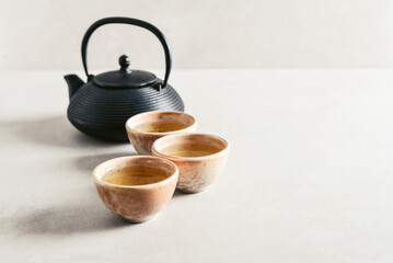 Black cast iron teapot and three ceramic cups of green tea - 764037218