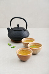 Black cast iron teapot and three ceramic cups of green tea - 764037227