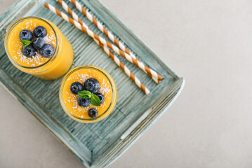 Refreshing and healthy mango smoothie with coconut flakes and fresh blueberries - 764037270