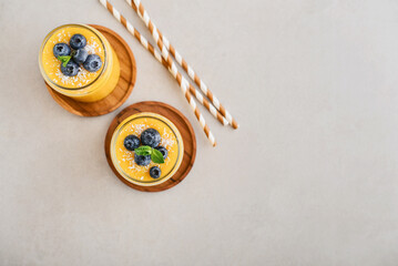 Refreshing and healthy mango smoothie with coconut flakes and fresh blueberries