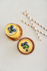 Refreshing and healthy mango smoothie with coconut flakes and fresh blueberries - 764037427