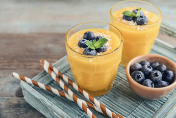 Refreshing and healthy mango smoothie in glasses with coconut flakes and fresh blueberries - 764037457