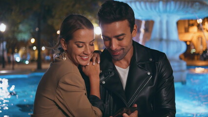 Happy sweethearts watching smartphone outdoors closeup. Loving couple having fun