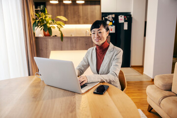A japanese middle-aged businesswoman typing on a laptop and working from home.