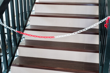 Plastic red and white warning chain links and wooden stair.